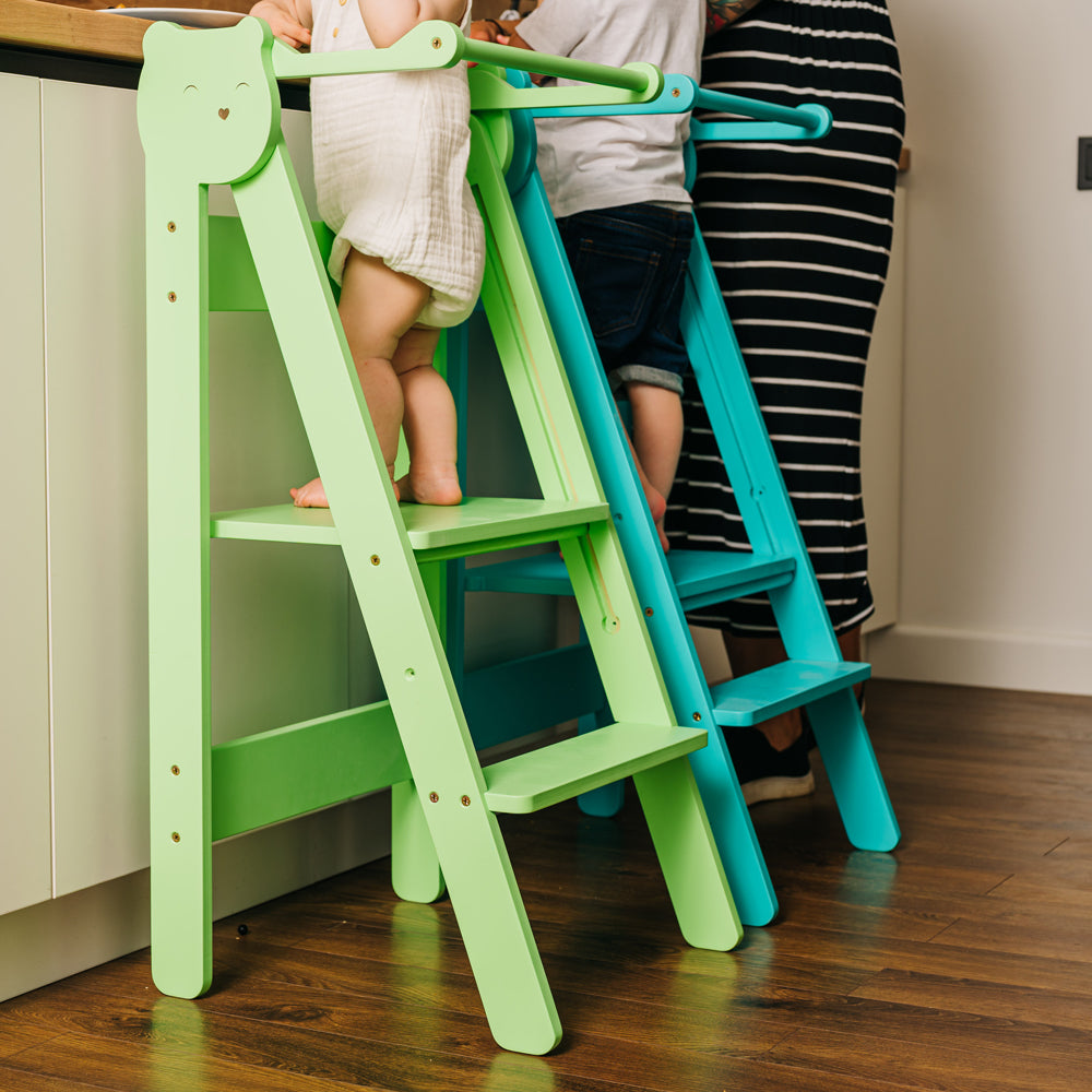 Zwei klappbare Tritthocker Lernstühle mit 2 Stufen in Grün und Blau im gelben Kinderzimmer nach Montessori und Pikler Prinzipien.