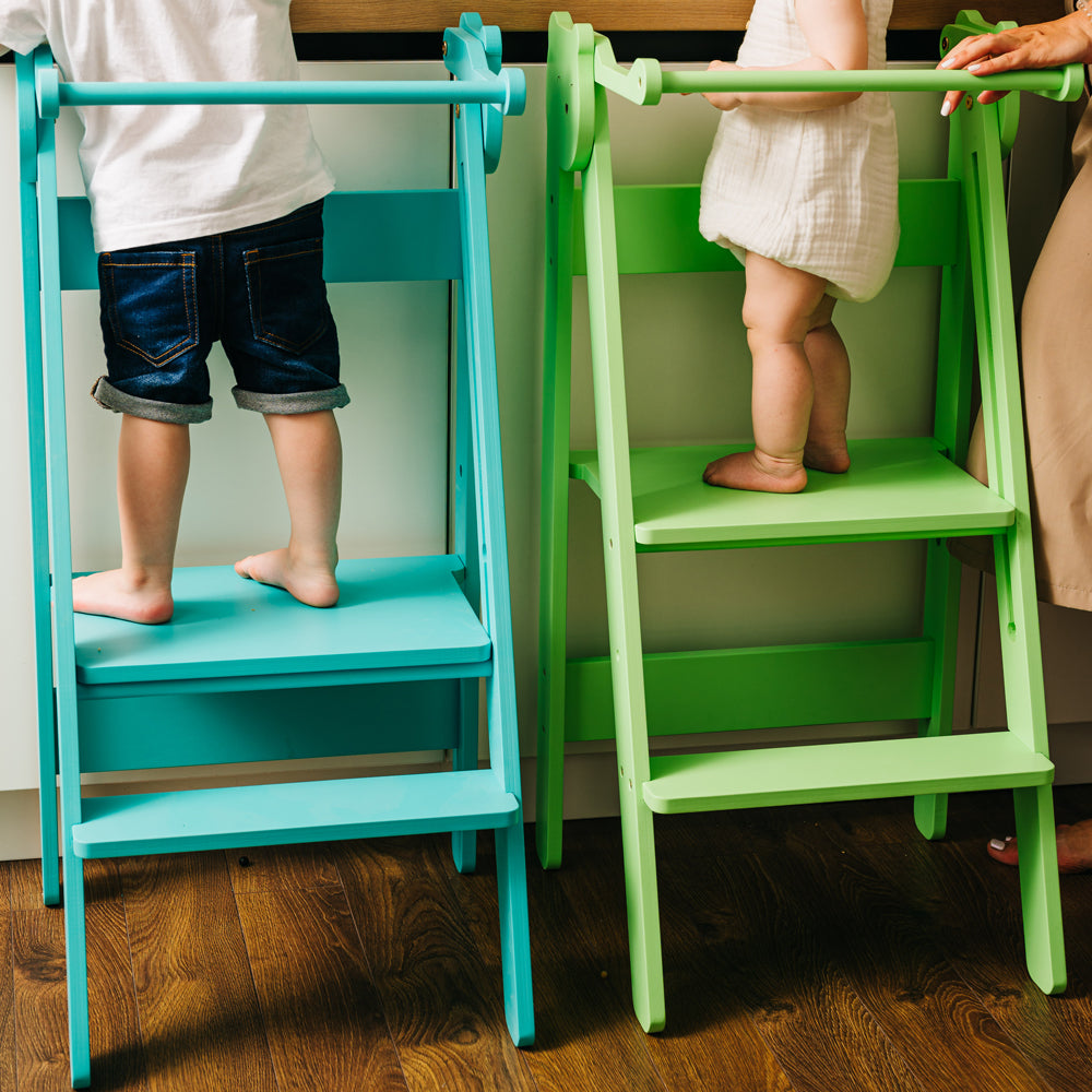Zwei höhenverstellbare Tritthocker Lernstühle in Blau und Grün im gelben Kinderzimmer, inspiriert von Pikler und Montessori Design.