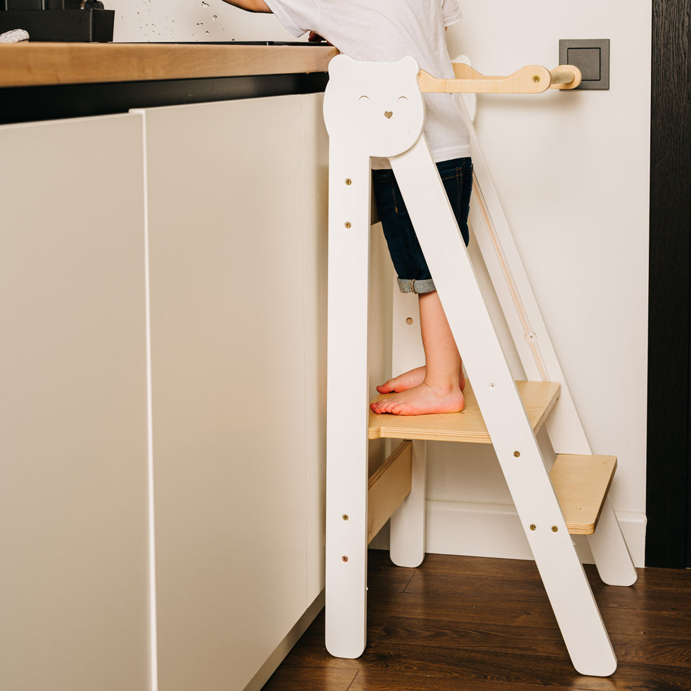 Kind steht auf klappbarem Tritthocker Lernstuhl mit 2 höhenverstellbaren Stufen im gelben Kinderzimmer, Pikler & Montessori Stil