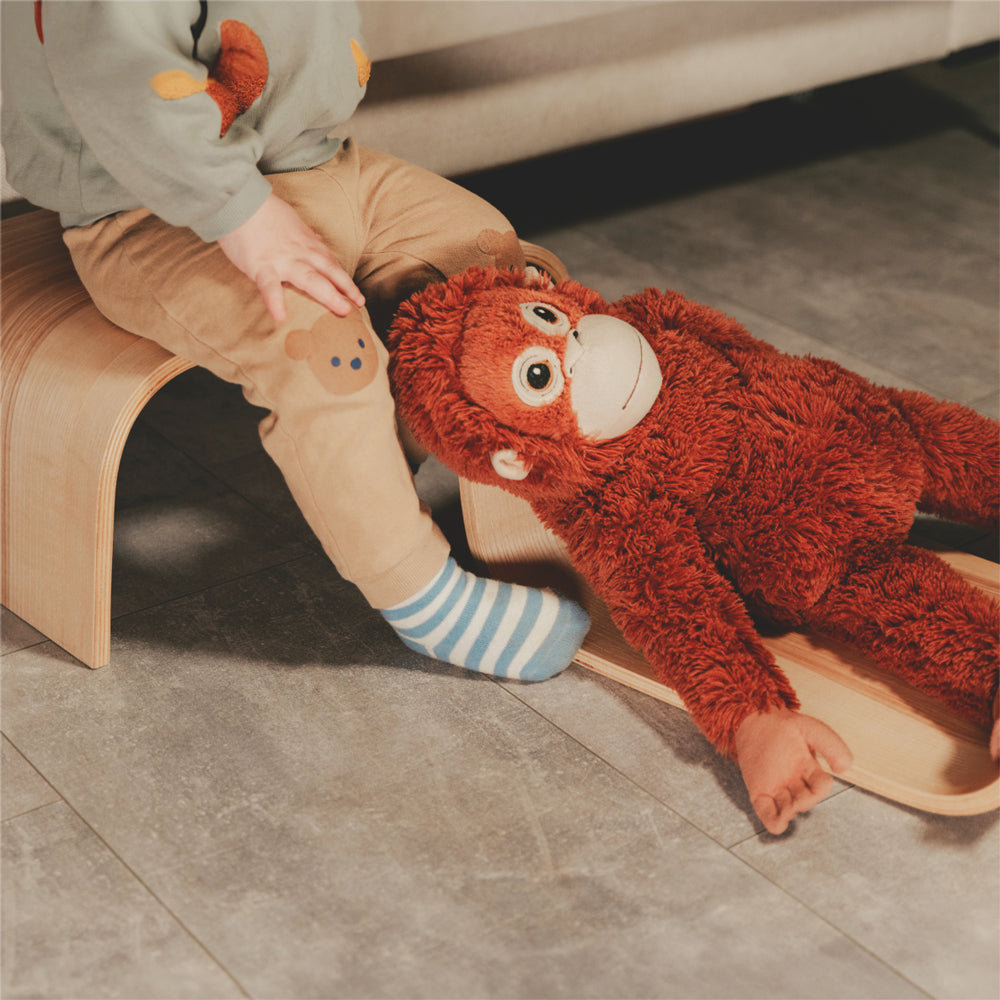Kinder sitzt auf naturfarbenem Tritthocker aus Birkenholz neben großem Kuschelaffen im Wohnzimmer, spielerisch und sicher.